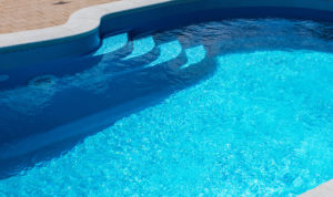 a swimming pool with a concrete pool deck